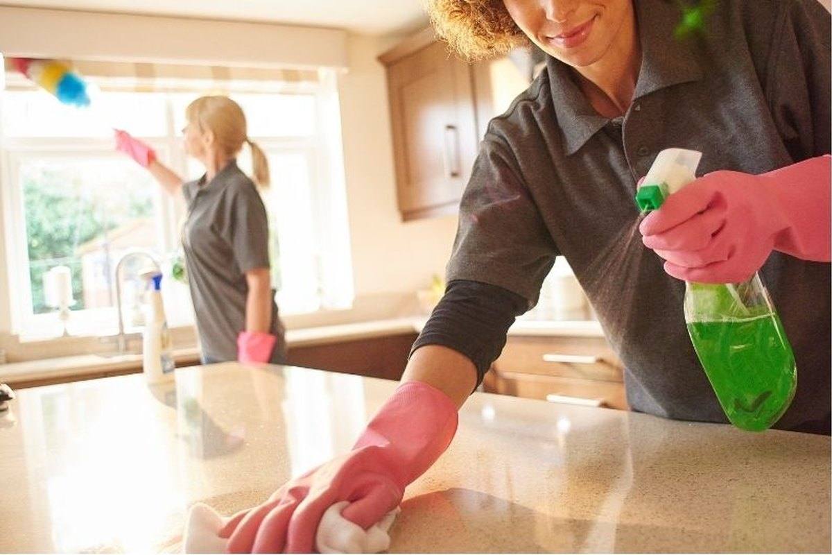 Deux personnes nettoyant un comptoir de cuisine et une fenêtre
